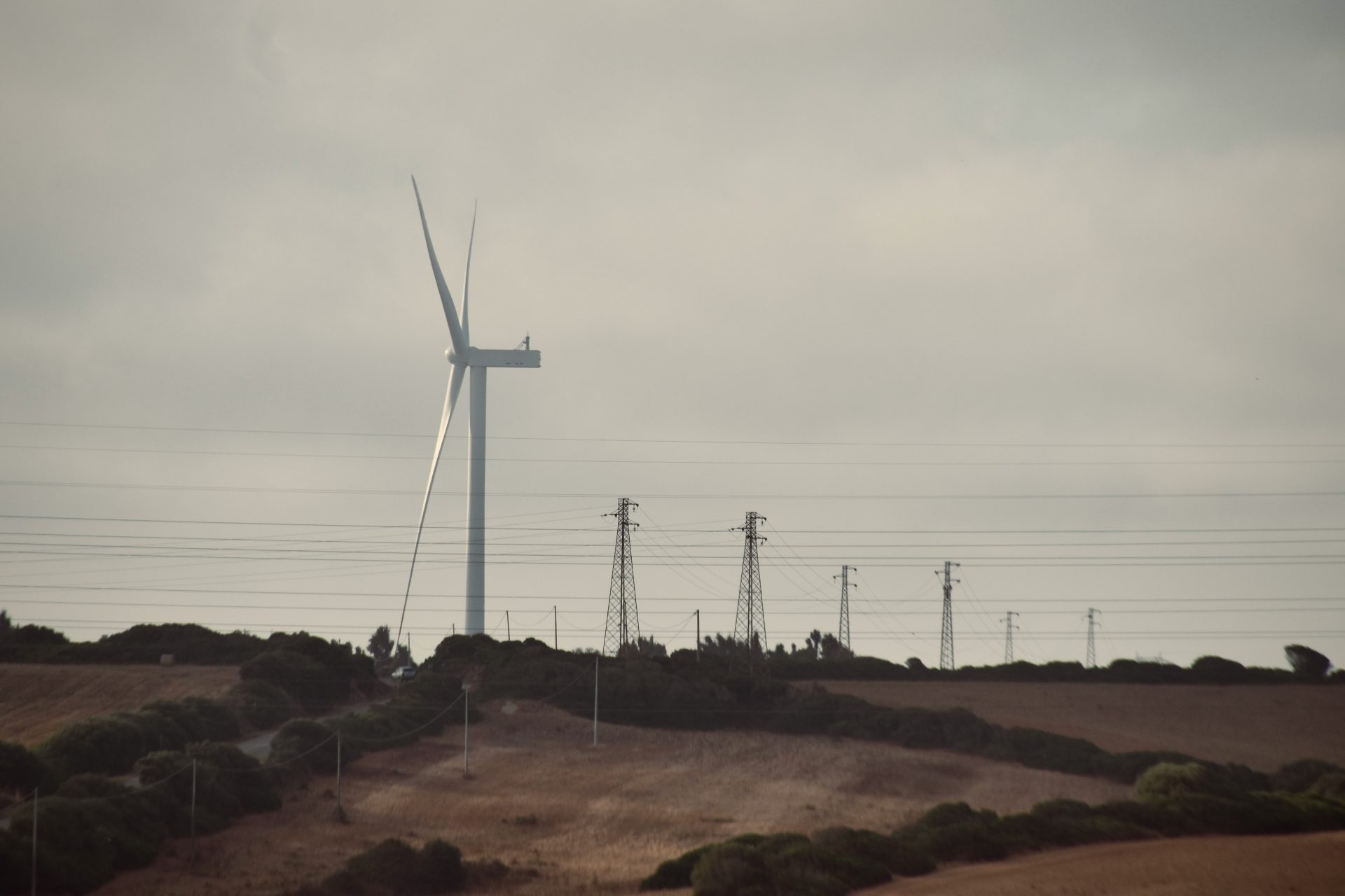 Une éolienne sur une colline avec des lignes électriques en arrière-plan